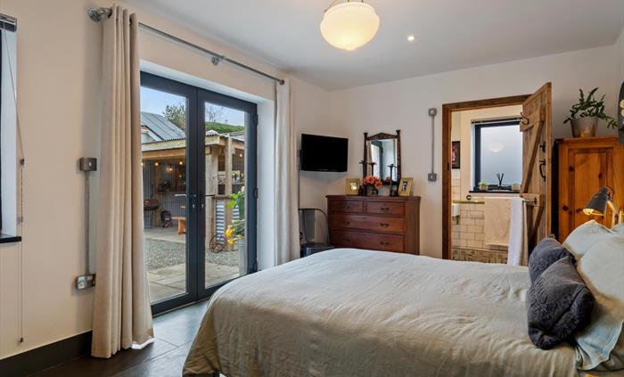 on the ground floor with french doors leading to patio and covered BBQ area, wall mounted smart TV, period central lampshade, cottage style wooden doo
